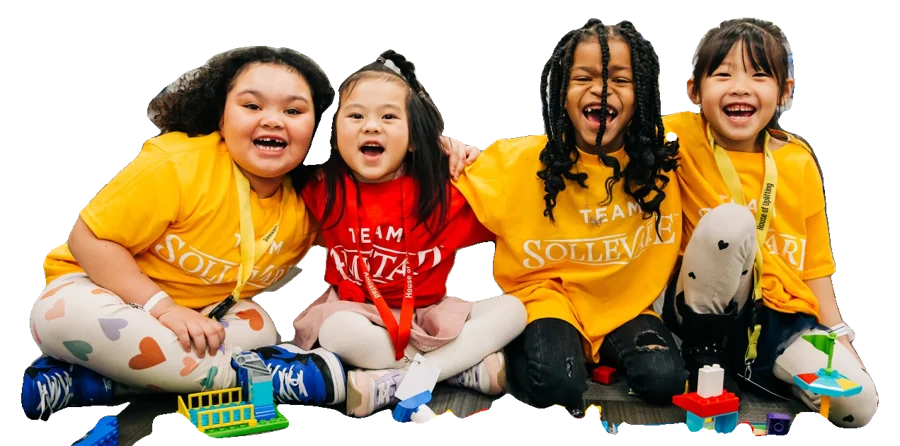 Four young kids sitting on the floor laughing with building blocks.
