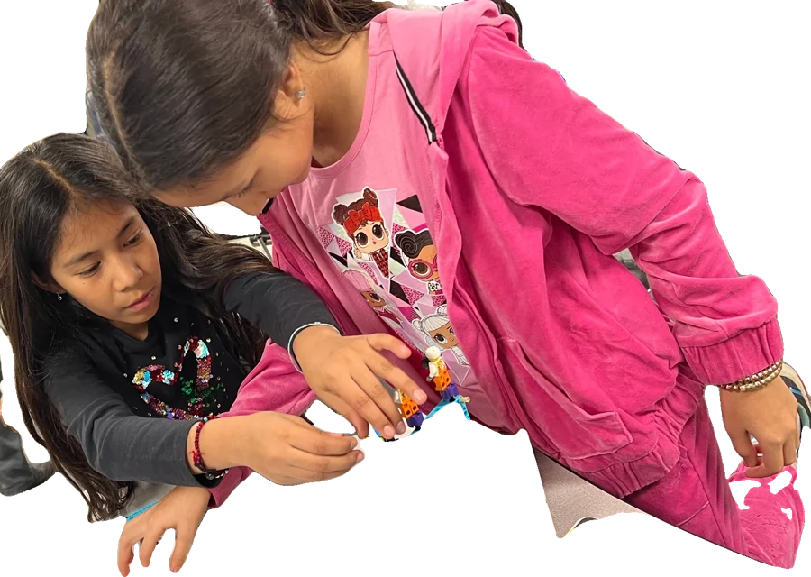Two girls building a tall machine together.