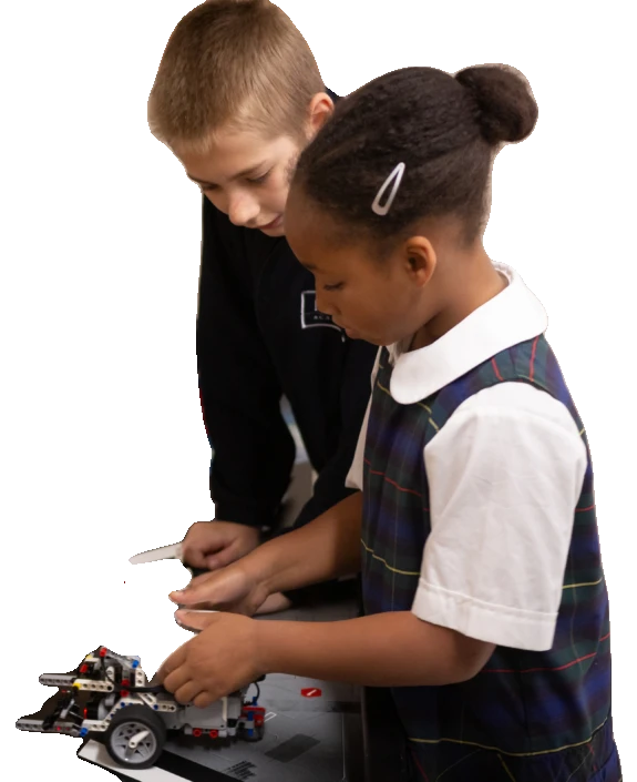 Two createMPLS students lean over a LEGO robot they are building together