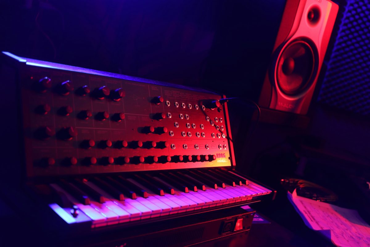 A synthesizer glowing red and purple in a dark studio