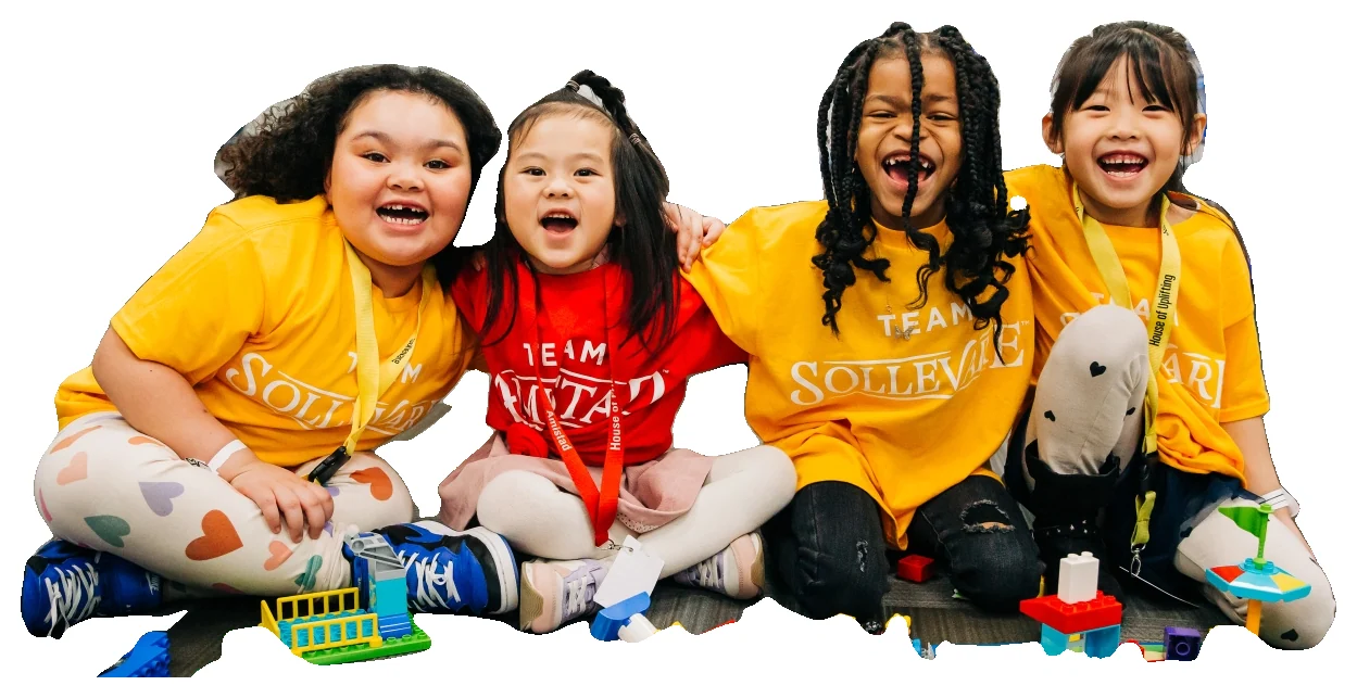 Four young createMPLS students laughing together on the floor with their LEGO builds.