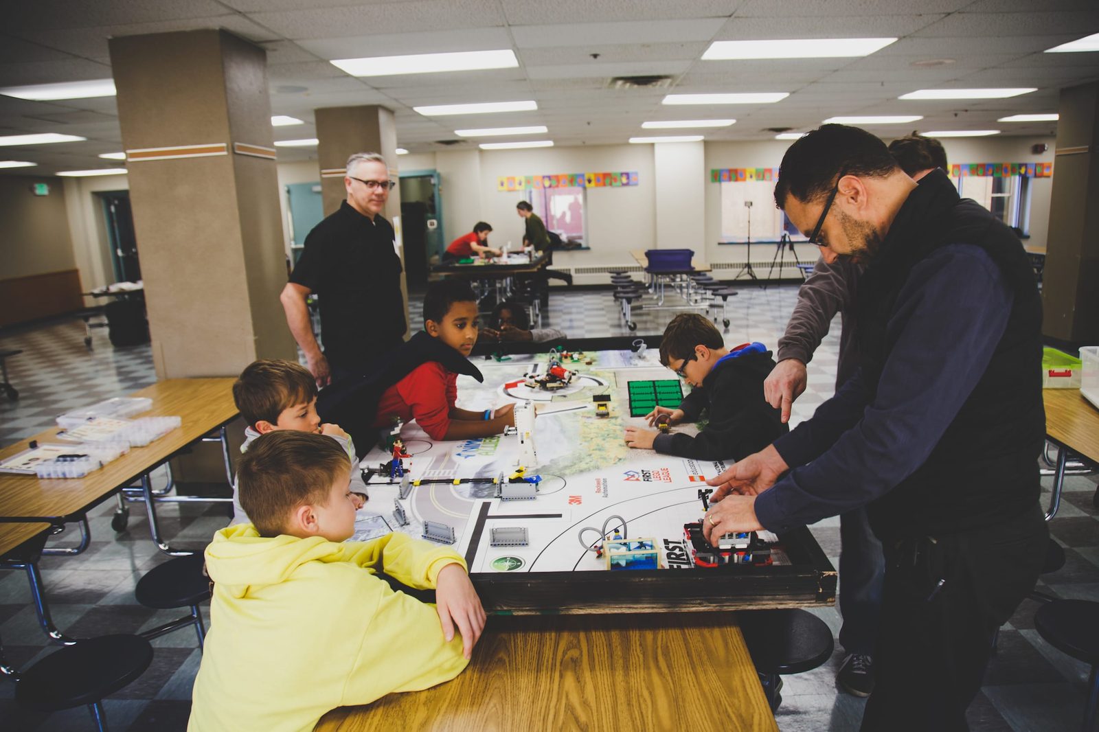 Students and coaches gather around a LEGO robotics competition table