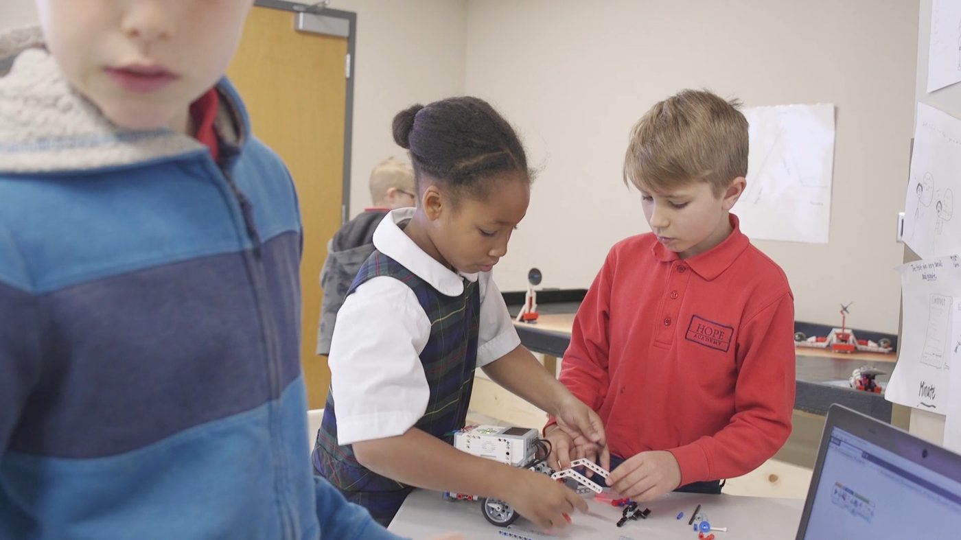 Two students build a LEGO robot together at a classroom table