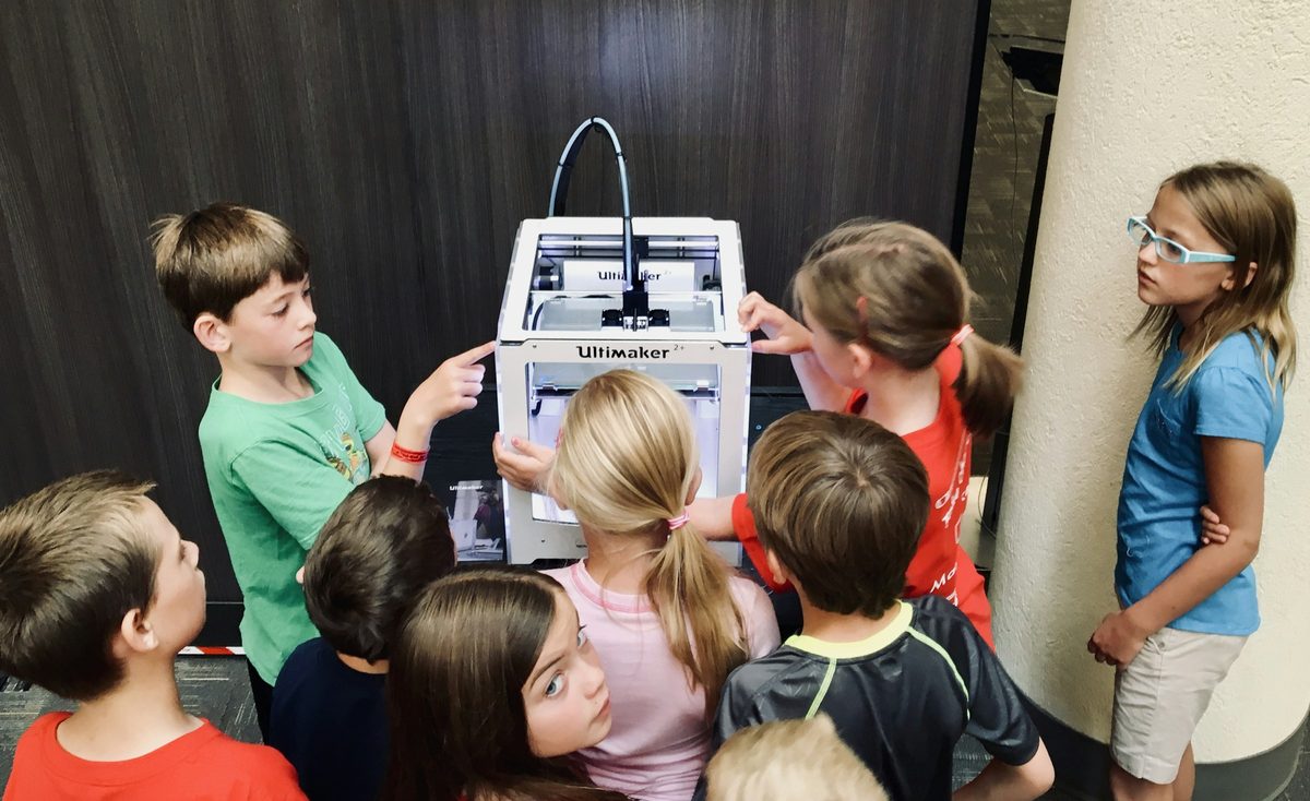Students gather around a desktop 3D printer